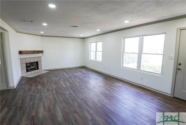 unfurnished living room with a fireplace, visible vents, dark wood finished floors, and crown molding