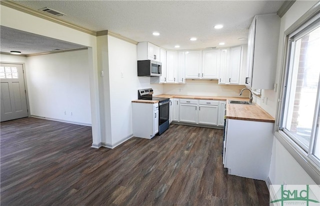 kitchen featuring visible vents, white cabinets, butcher block counters, stainless steel appliances, and a sink