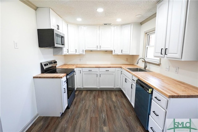 kitchen featuring appliances with stainless steel finishes, white cabinetry, a sink, and wood counters