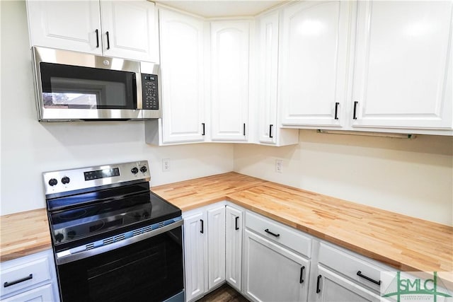 kitchen featuring wooden counters, appliances with stainless steel finishes, and white cabinets