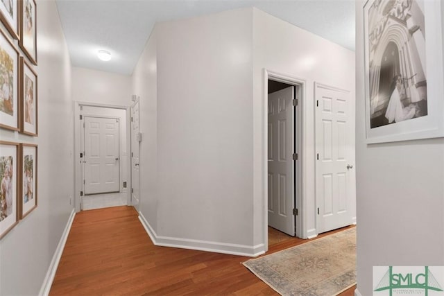 hallway with wood finished floors and baseboards