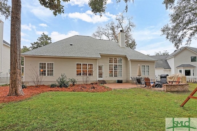 back of property with entry steps, a patio area, a lawn, and a chimney