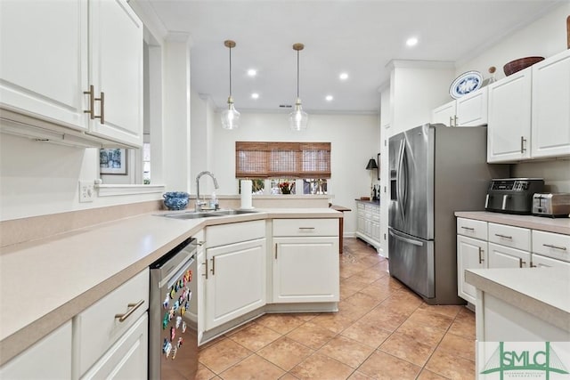 kitchen featuring pendant lighting, stainless steel appliances, light countertops, white cabinetry, and a sink