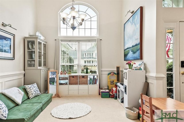 game room featuring a wainscoted wall, carpet floors, a chandelier, and a decorative wall