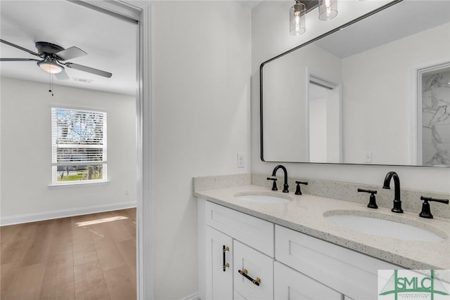 bathroom with double vanity, baseboards, a sink, and wood finished floors