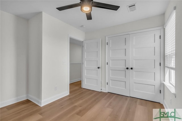 unfurnished bedroom featuring light wood-style flooring, multiple windows, visible vents, and baseboards