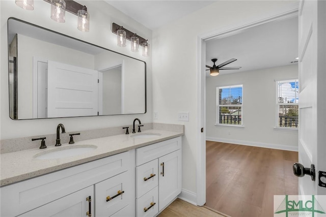 bathroom with double vanity, ceiling fan, a sink, and wood finished floors