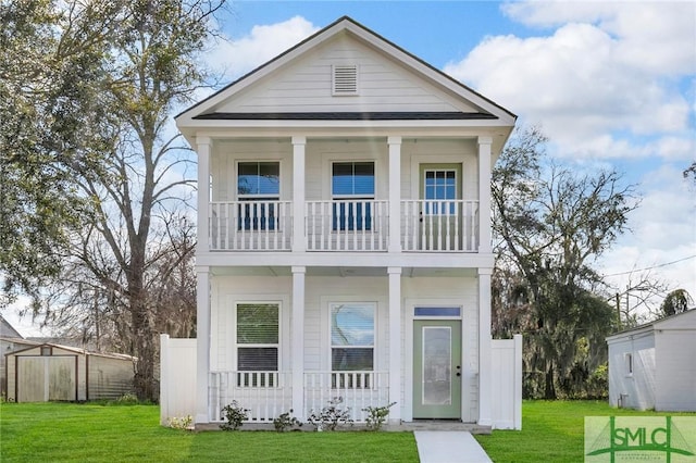 neoclassical home with a porch, a balcony, a shed, an outdoor structure, and a front lawn