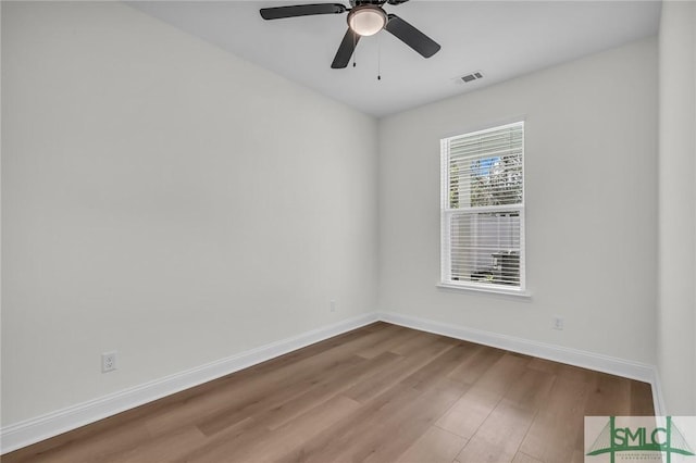 empty room featuring ceiling fan, wood finished floors, visible vents, and baseboards