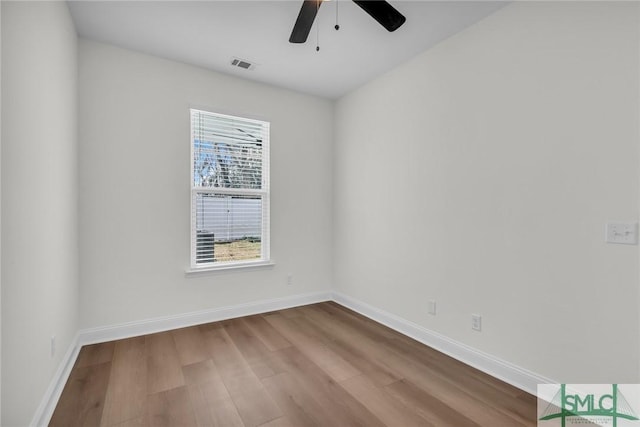 empty room with a ceiling fan, visible vents, baseboards, and wood finished floors