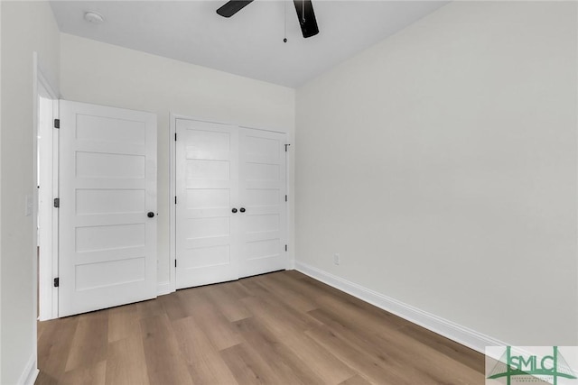 unfurnished bedroom with a closet, ceiling fan, baseboards, and wood finished floors