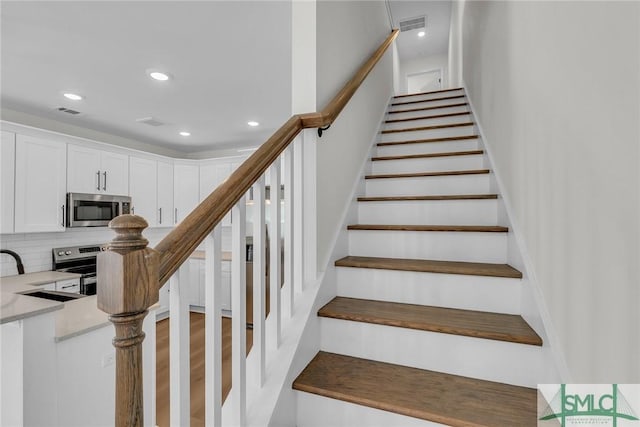 stairway with recessed lighting, visible vents, and wood finished floors