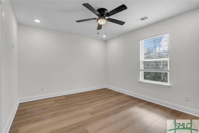 spare room featuring a ceiling fan, wood finished floors, visible vents, and baseboards