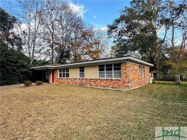 view of front of property featuring a carport, brick siding, fence, and a front lawn