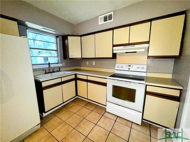 kitchen with light countertops, white appliances, a sink, and under cabinet range hood