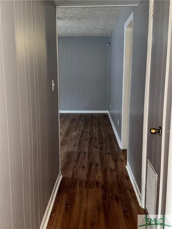 hall featuring visible vents, dark wood finished floors, and baseboards