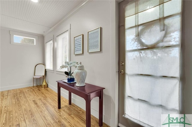 doorway to outside featuring crown molding, baseboards, and light wood-style floors