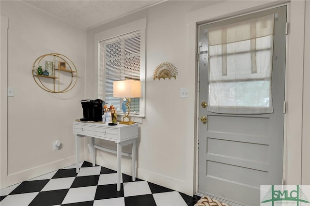 foyer featuring dark floors, a textured ceiling, and baseboards