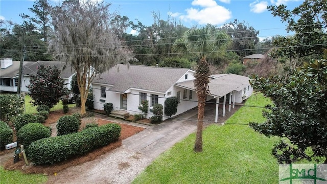 exterior space with driveway, roof with shingles, and a front yard