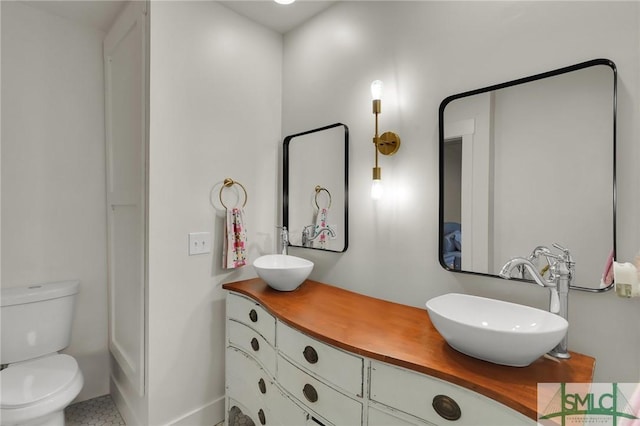 full bathroom with double vanity, a sink, and toilet