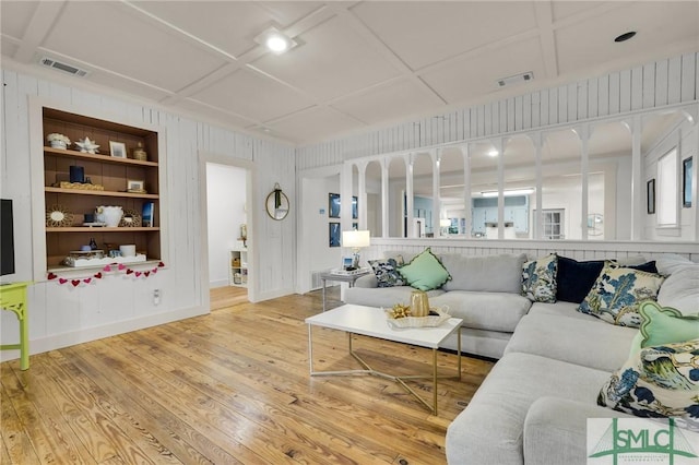 living area with light wood-style floors, coffered ceiling, visible vents, and built in features