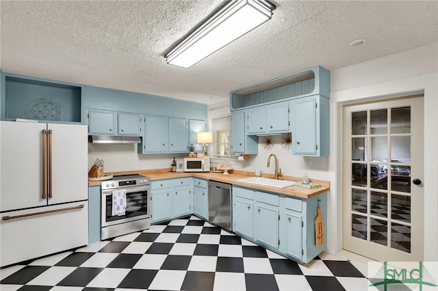 kitchen with dark floors, stainless steel appliances, a sink, blue cabinets, and under cabinet range hood