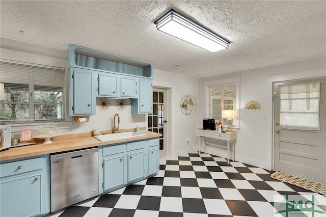 kitchen with baseboards, dishwasher, dark floors, blue cabinetry, and a sink