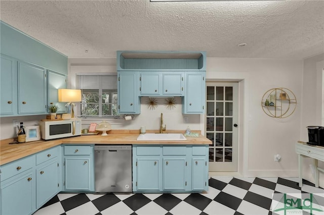 kitchen featuring dishwasher, white microwave, dark floors, light countertops, and a sink