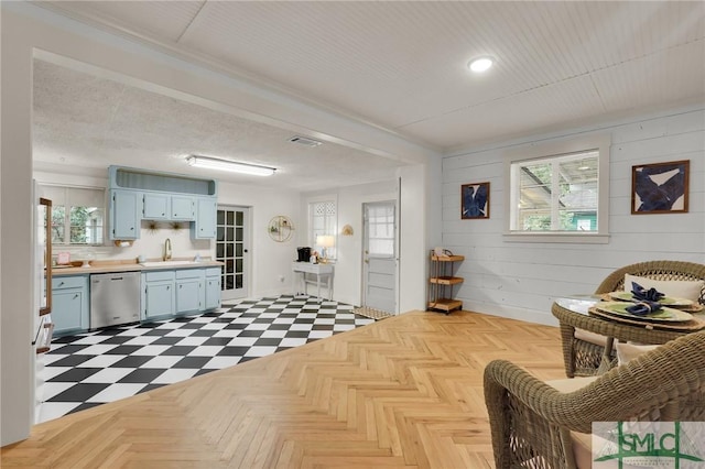 sitting room with light floors, wooden walls, visible vents, and a healthy amount of sunlight