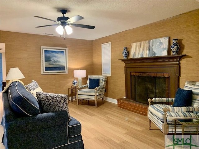 living area with a textured ceiling, a ceiling fan, baseboards, visible vents, and light wood-style floors