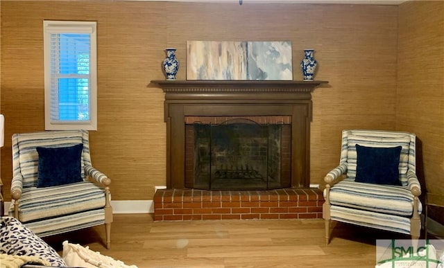 sitting room with a brick fireplace and wood finished floors