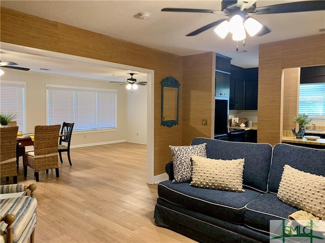 living room with ceiling fan, wood finished floors, and baseboards