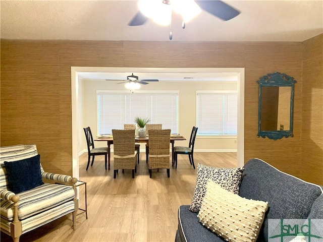 dining space featuring a ceiling fan, light wood-type flooring, and baseboards