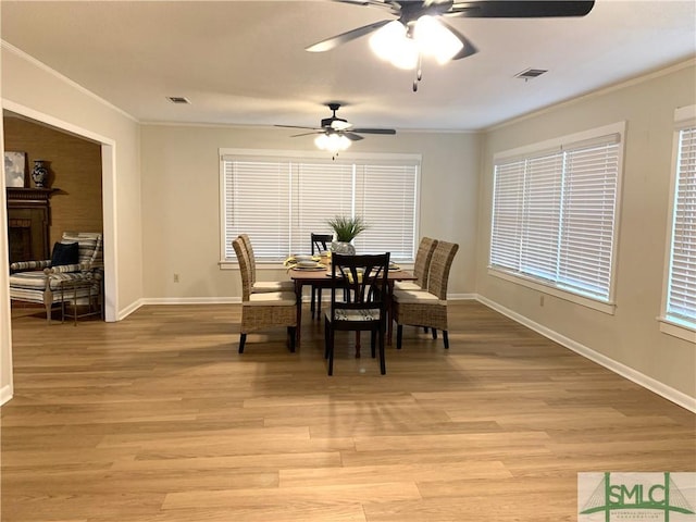 dining area with light wood finished floors, baseboards, visible vents, and crown molding