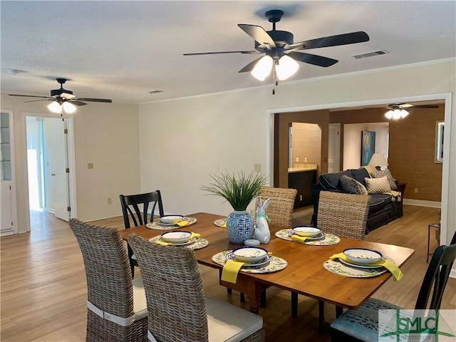 dining space with ornamental molding, visible vents, light wood-style flooring, and baseboards
