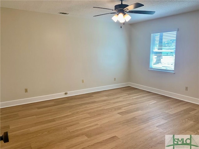 unfurnished room with light wood-type flooring, baseboards, visible vents, and a textured ceiling
