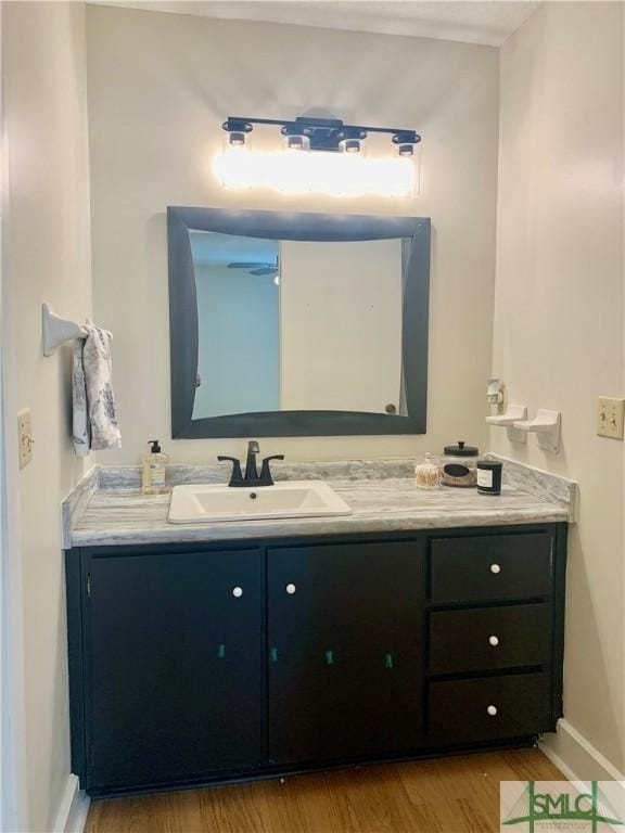 bathroom featuring vanity, baseboards, and wood finished floors