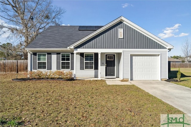 view of front facade featuring a garage, a front yard, roof mounted solar panels, and fence