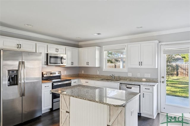 kitchen with appliances with stainless steel finishes, light stone countertops, white cabinetry, and a center island