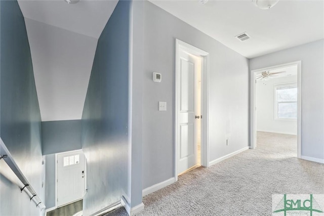 corridor with light colored carpet, visible vents, and baseboards