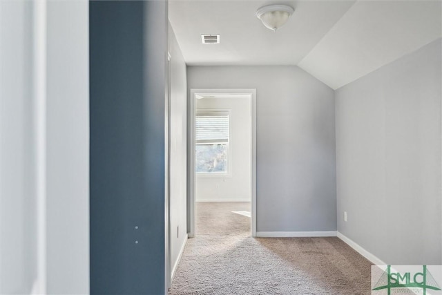 interior space featuring baseboards, lofted ceiling, visible vents, and light colored carpet