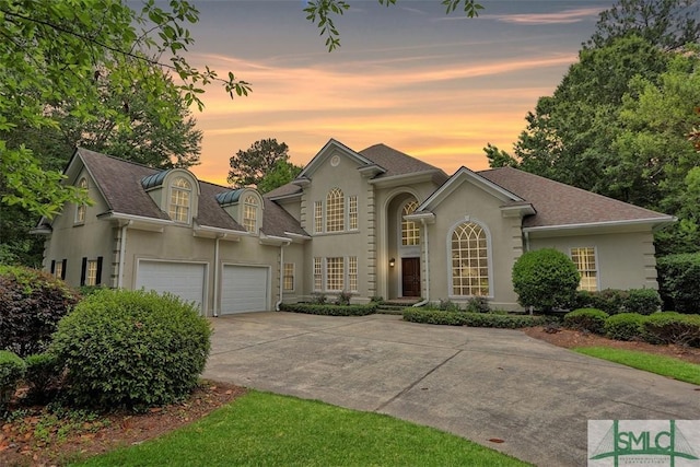 view of front facade with a garage, concrete driveway, and stucco siding