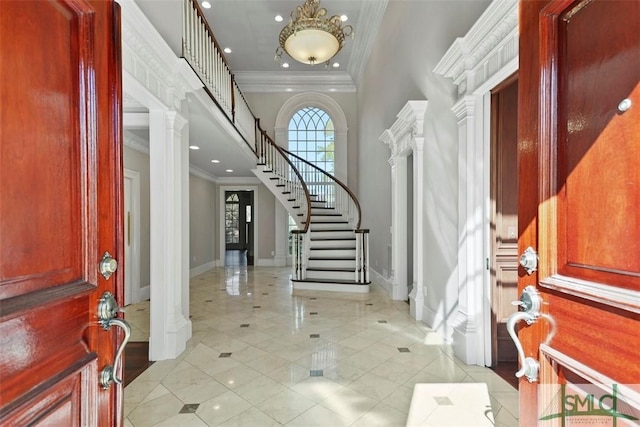 foyer with ornate columns, stairs, baseboards, and crown molding