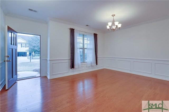 interior space featuring an inviting chandelier, visible vents, wood finished floors, and ornamental molding