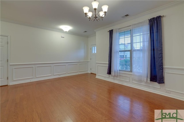 unfurnished room with an inviting chandelier, visible vents, wood finished floors, and ornamental molding