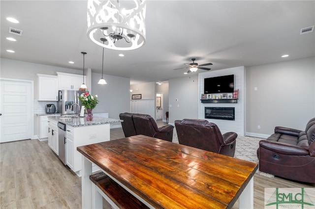 dining space featuring recessed lighting, a fireplace, visible vents, and ceiling fan with notable chandelier