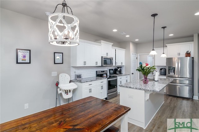 kitchen featuring appliances with stainless steel finishes, a center island, white cabinetry, and light stone counters