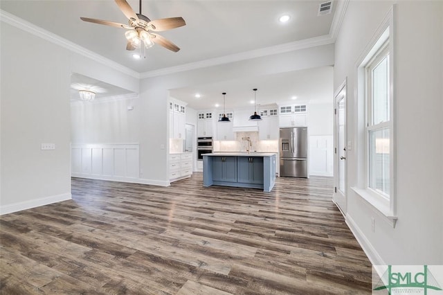 kitchen featuring a kitchen island with sink, stainless steel appliances, white cabinets, light countertops, and glass insert cabinets