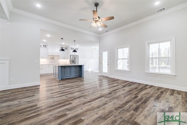 unfurnished living room with dark wood-style floors, ornamental molding, visible vents, and baseboards