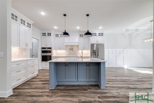 kitchen with light countertops, appliances with stainless steel finishes, glass insert cabinets, and pendant lighting